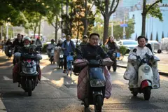 Pessoas dirigindo scooter elétrica em Pequim