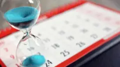 ساعة رملية بها رمال زرقاء موضوعة على لوحة بها أيام الشهر