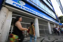 Fachada de um prédio do INSS com pessoas passando em frente