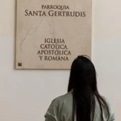 Mulher de costas olhando para placa de paróquia