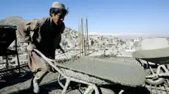 یک کاگر افغان در حال انتقال سمنت 