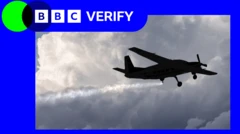 بادلوں میں اڑتا ایک چھوٹا طیارہ آسمان میں باریک ذرات کا چھڑکاؤ کر رہا ہے، پیچھے ایک لمبی سفید لکیر بن رہی ہے۔ اوپر بائیں کونے میں بی بی سی ویریفائی کا لوگو دکھائی دیتا ہے۔