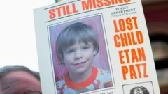 Un hombre sostiene un periódico en el que se ve una foto de Etan Patz y el titular en inglés "aún desaparecido"