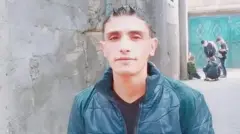 Ahmed Alhasant, ainda com peso saudável, usando uma jaqueta verde escura ao lado de uma parede