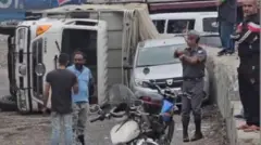 مواطنون وعنصر من الدرك اللبناني يقفون بجوار الشاحنة المقلوبة