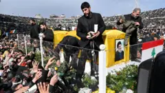 Hezbollah Hassan NasrallahとHashem Safi al -dinの2年間の2人の前年の葬儀の参加者は、彼らを人々に置くための安全保障職員の象徴です。