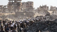 جموع من الفلسطينيين عند مركز لتوزيع المساعدات قُرب معبر زيكيم الحدودي، تحيط بهم أنقاض مبانٍ تعرّضتْ للتفجير.