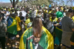 Mulher com bandeira verde e amarela de Bolsonaro em ato favorável ao ex-presidente