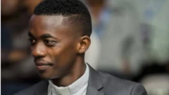 'Bishop Gafaranga' yambaye ikoti rijya gusa n'ivu hamwe n'ishati iriho ikora rimenyerewe ku bapasiteri