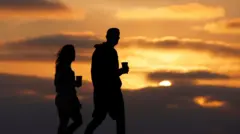 زوجان يتنزهان على طول ساحل لا جولا عند غروب الشمس في أمسية صيفية دافئة في 3 أغسطس/آب 2025 في سان دييغو، كاليفورنيا.