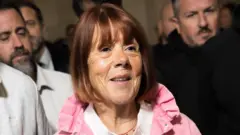 Gisèle Pelicot con una sonrisa rodeada de hombres a la salida de la corte