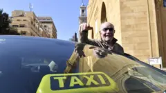 صورة لسائق اجرة خارج سيارته خلال تحرك احتجاجي لسائقي سيارات الأجرة في وسط بيروت.