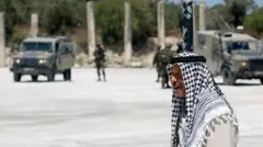 Un hombre palestino camina cerca de tropas israelíes en el yacimiento arqueológico de Sebastia, en Cisjordania ocupada (29 de junio de 2026) 