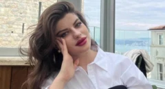 Ayşe Tokyaz beyaz gömlekle oturuyor