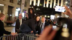 María Corina Machado salta as grades de segurança diante do Grand Hotel, em Oslo, para cumprimentar apoiadores que aplaudem, enquanto seguranças observam