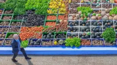 O presidente Luiz Inácio Lula da Silva segura uma verdura nas mãos e caminha em frente a produtos da agricultura familiar durante o lançamento do Plano Safra da Agricultura Familiar 2024/2025, no Palácio do Planalto, em julho de 2024