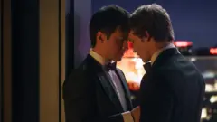 Cena de 'Heated Rivalry': Hudson Williams como Shane Hollander e Connor Storrie como Ilya Rozanov, de terno e olhos fechados