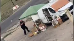 Чоловік стоїть біля машини і намагається сховатися від дрона