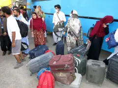 stanovnici Teherana sa koferima ispred autobusa