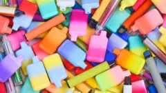 Uma foto de vários vapes coloridos e brilhantes, de diferentes formatos e tamanhos.