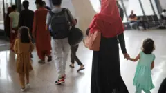 Kundi la watu wakiwemo wanawake na watoto wakiwasili kwenye uwanja wa ndege wa Dulles baada ya kukimbia utekaji wa Taliban wa Afghanistan Agosti 27, 2021.