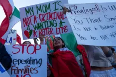 Uma jovem com uma bandeira do México e um cartaz em inglês que diz: "Minha mãe não é uma criminosa por querer uma vida melhor"