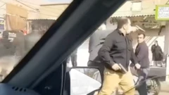 Una captura de pantalla de un video tomado desde un automóvil muestra a dos hombres armados vestidos de civil, uno de los cuales apunta directamente a alguien que se encuentra fuera del plano.