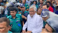 আমান উল্লাহ আমানকে নিয়ে যাচ্ছে পুলিশ। 