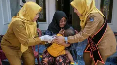 Seorang petugas kesehatan memberikan vaksin campak kepada seorang anak selama imunisasi simultan di Surabaya pada 15 September 2025