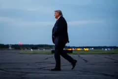 Donald Trump, visto de perfil, caminando en solitario por la pista de un aeropuerto.
