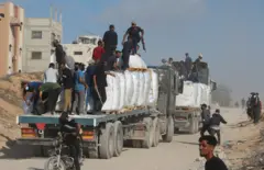 فلسطينيون من العشائر يحملون أسلحة لتأمين شاحنات المساعدات في بيت لاهيا شمال قطاع غزة، 25 يونيو/ حزيران 2025.