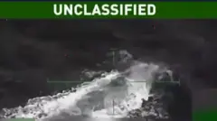 Imagen difuminada en blanco y negro en la que se percibe una especie de submarino que empieza a reflotar en el mar. 