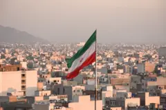 Drapeau iranien flottant sur fond de paysage urbain à Téhéran, Iran