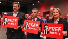 SPD'nin yeni eş genel başkanları Lars Klingbeil ve Bärbel Bas'ın arasında Özgür Özel duruyor. Fotoğraftaki çok sayıda kişi İmamoğlu'na Özgürlük pankartları taşıyor.