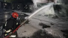 Пожарный тушит огонь водой из шланга