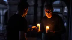 Dos personas se iluminan con velas luego del apagón en españa y portugal 