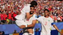 Two football players hug diasef, anoda one dey for back smiling