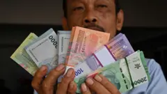 Seorang pria memperlihatkan uang kertas rupiah barunya, yang akan diberikan kepada anggota keluarga selama festival Idul Fitri yang menandai berakhirnya bulan suci Ramadan, di Jakarta pada 28 Maret 2024. (Foto oleh 