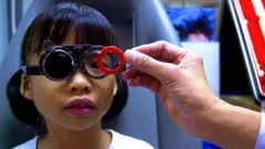 Seorang anak perempuan melakukan cek mata. 