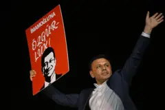 Özgür Çelik elinde "İmamoğlu'na Özgürlük" yazılı bir döviz tutuyor ve sol kolunu yukarıya kaldırıyor