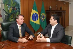Bolsonaro e Alcolumbre sentados em uma mesa, conversando