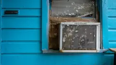 Aparelho de ar-condicionado instalado na janela de uma casa de madeira pintada de azul
