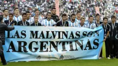 La selección argentina tras una pancarta que dice "Las Malvinas son argentinas".
