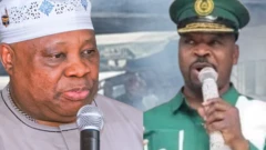 Gomina Ademola Adeleke wọ aṣọ buba, mu ẹrọ gbohungbohun lọwọ, MC Oluomo wọ aṣọ ẹgbẹ NURTW ati fila, oun naa mu gbohungbohun lọwọ