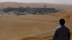 Um homem de costas observa, à distância, o centro de produção de gás liquefeito no campo de Shaybah, na Arábia Saudita