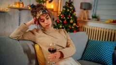 Młoda kobieta pijąca czerwone wino podczas świąt Bożego Narodzenia.