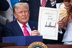 El presidente estadounidense Donald Trump, acompañado de legisladores republicanos, sostiene el acta del Gran y Hermoso Proyecto de Ley durante un picnic militar familiar del Día de la Independencia en el Jardín Sur de la Casa Blanca el 4 de julio de 2025 en Washington, DC. (Foto: Samuel Corum/Getty Images)