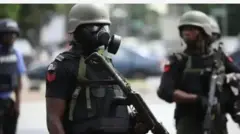 Aworan yii ṣafihan awọn ọlọpaa ọkunrin meji, wọn gbe ibọn dani, dira ogun daadaa. Ọkan nini wọn bo imu rẹ pẹlu irinṣẹ kan, o si fi igo dudu si oju. Ọlọpaa kan naa tun n han fẹẹrẹfẹ lapa ẹyin, oun wọsọ alawọ aro, nigba ti awọn meji yoku wọ aṣọ dudu.