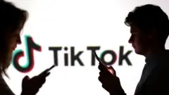 Подростки смотрят в свои телефоны на фоне логотипа TikTok 