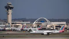 লস অ্যাঞ্জেলেস বিমানবন্দরে দাঁড়িয়ে আছে কয়েকটি বিমান, পেছনে কয়েকটি ভবন